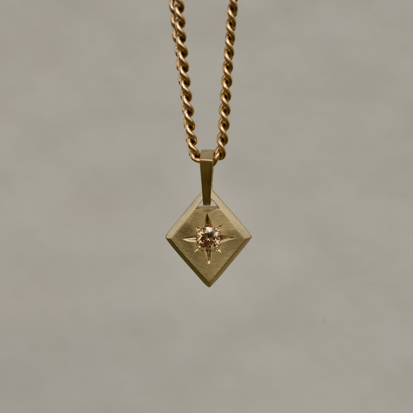 Lozenge-shaped tag pendant with star set round champagne round brilliant cut diamond