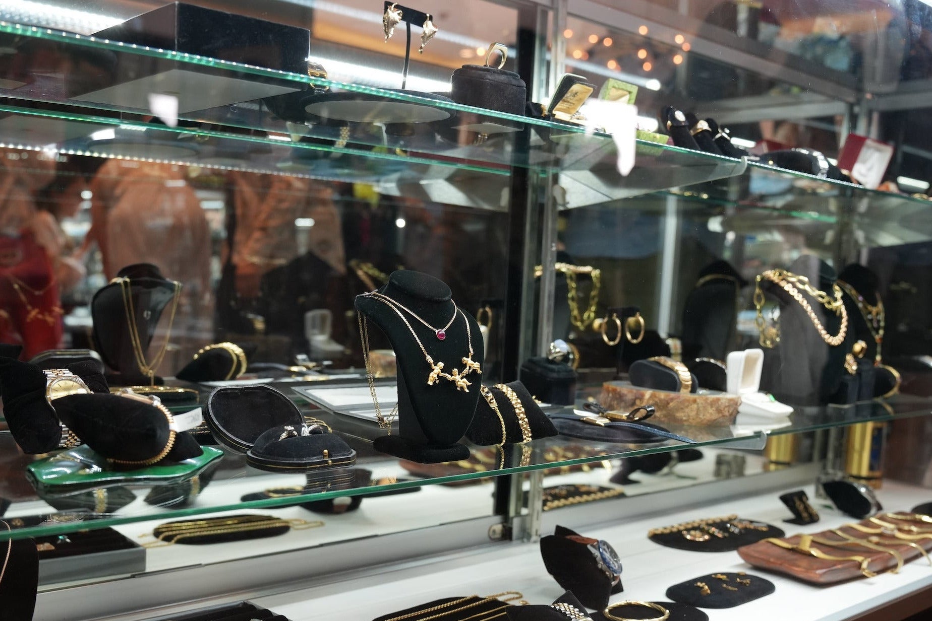 Display case with jewelry including watches and necklaces in a store setting.