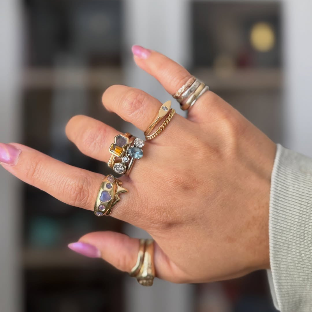 Hand wearing multiple rings with gemstones against a blurred background
