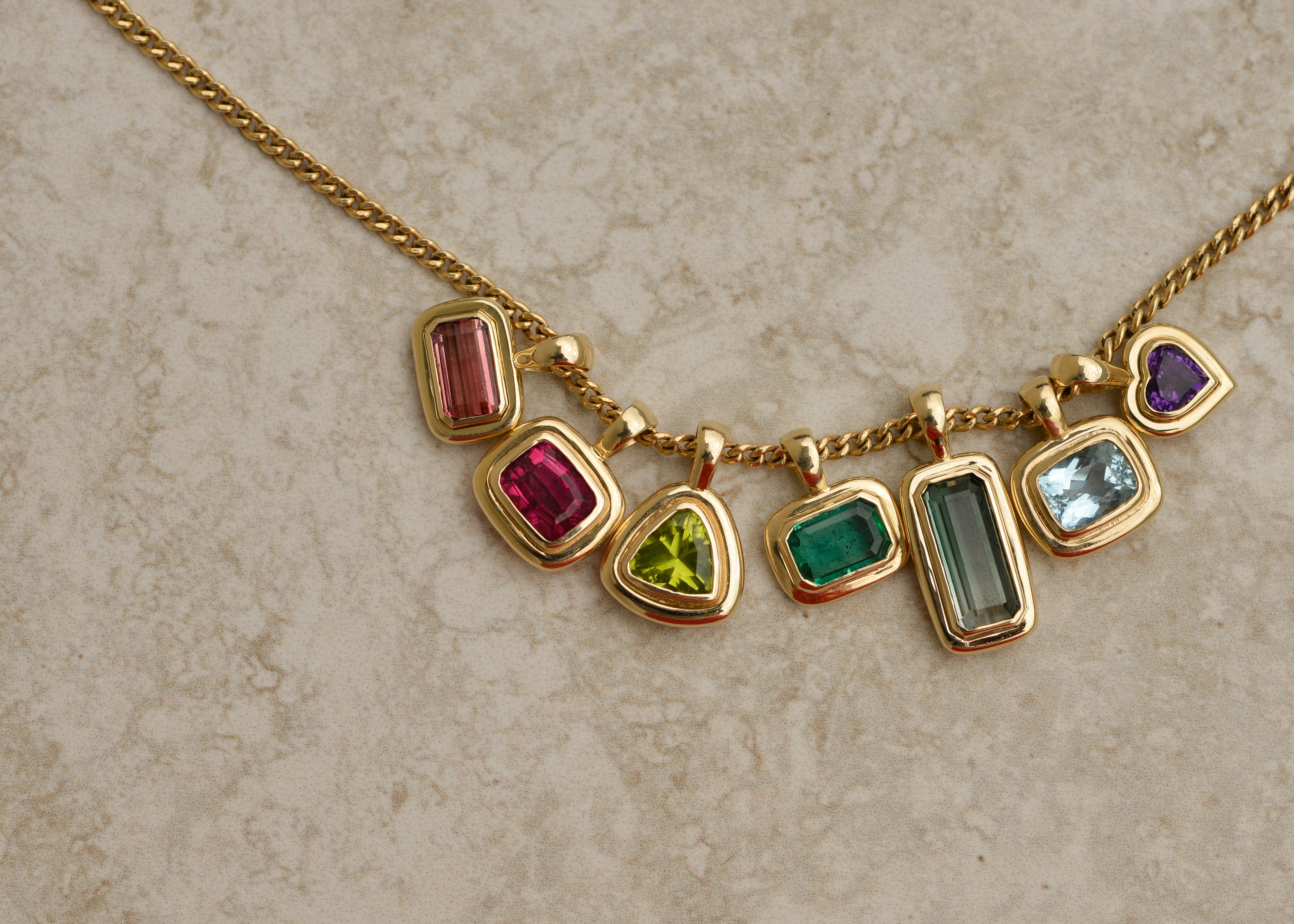 Gold necklace with colorful gemstones on a textured surface