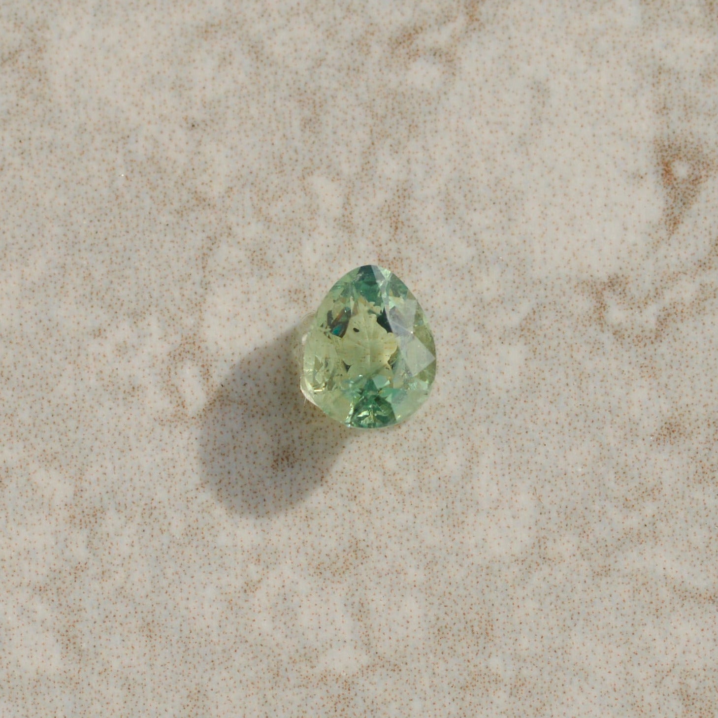 Green gemstone on a beige textured surface