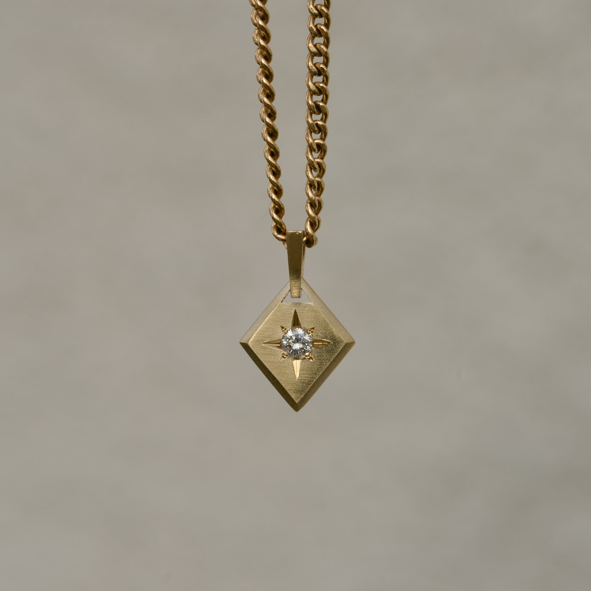 Lozenge-shaped tag pendant with star set round white round brilliant cut diamond