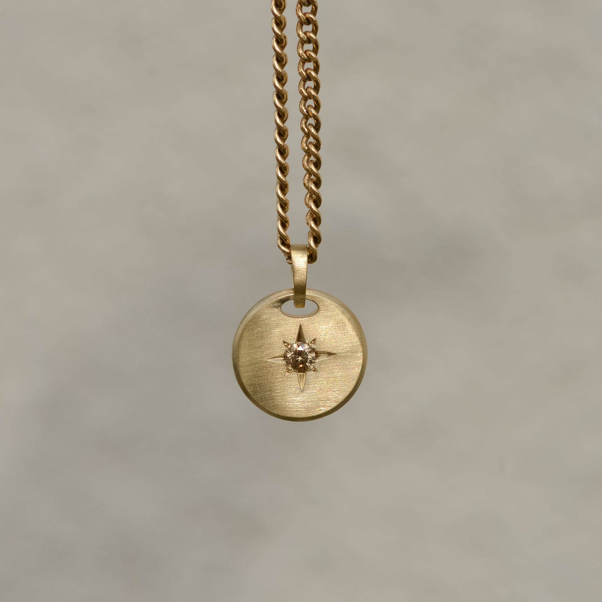 Round-shaped tag pendant with star set champagne round brilliant cut diamond