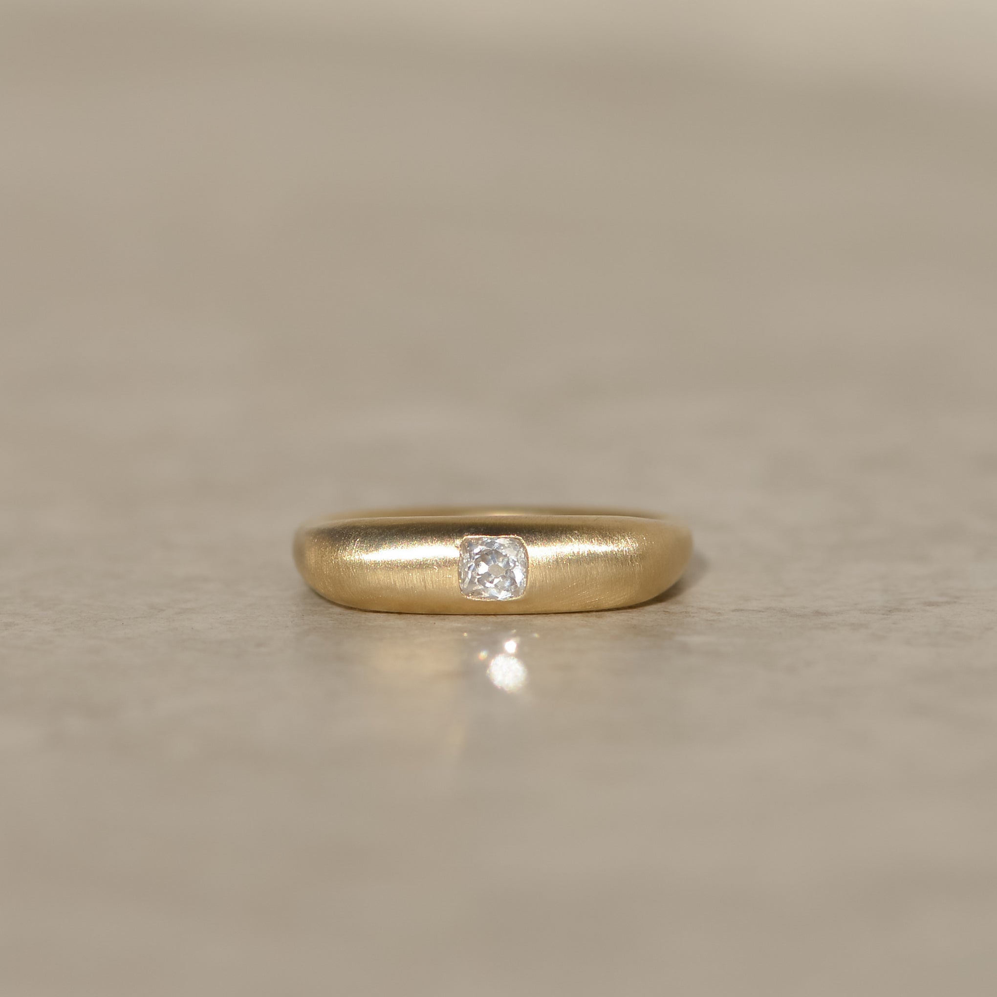 14k gold square band ring with a brushed finish and flush set with a 0.25 carat old mine cut diamond
