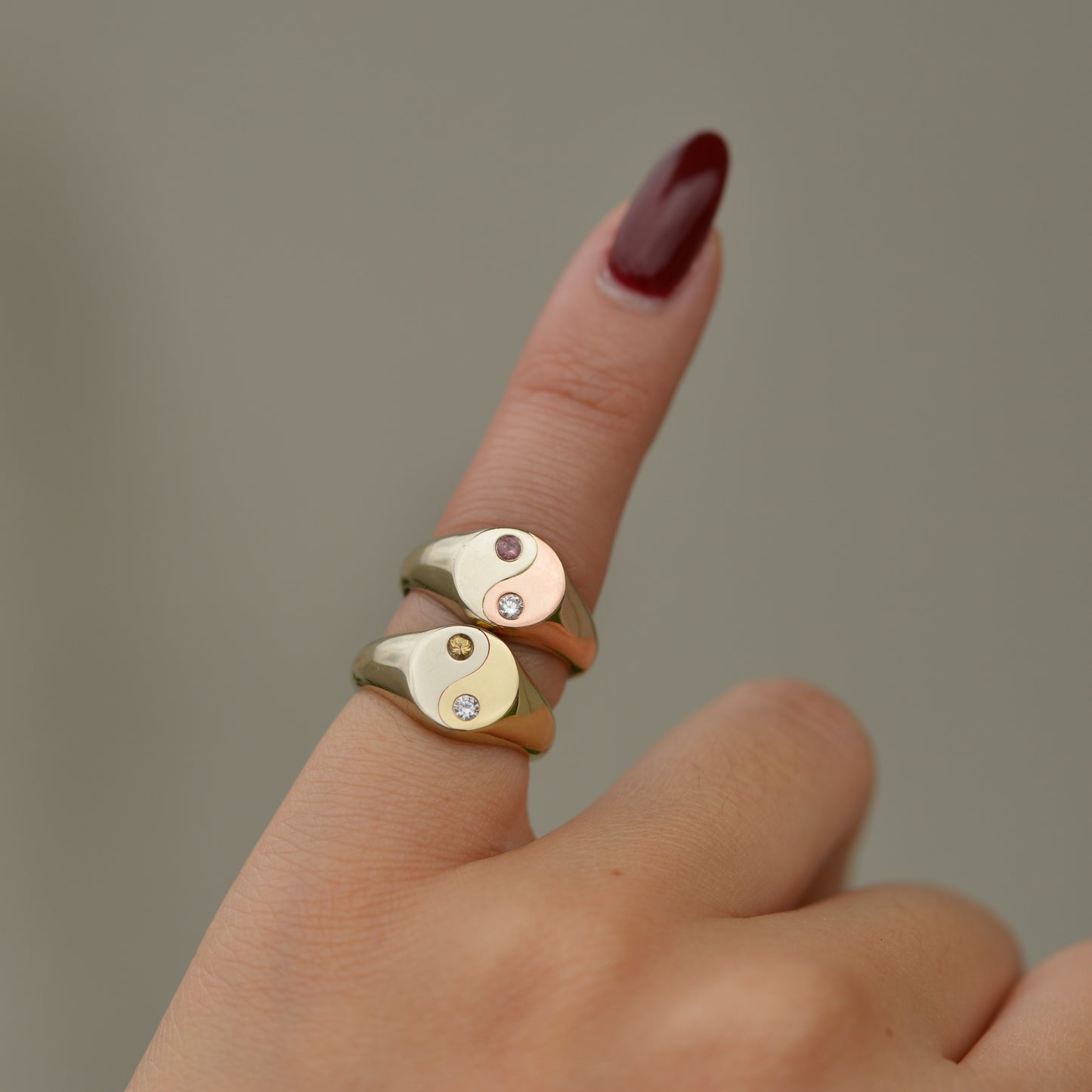two gold rings with a yin yang design on a pinky finger